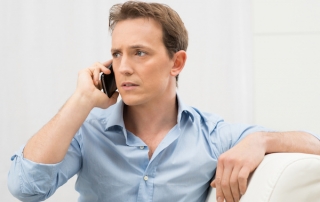 Man on phone looking worried, IRS tax scam