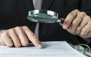 Man with magnifying glass auditing documents, audit advice from tax attorney