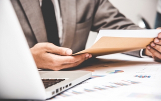 Businessman pulling out business document from brown envelope.